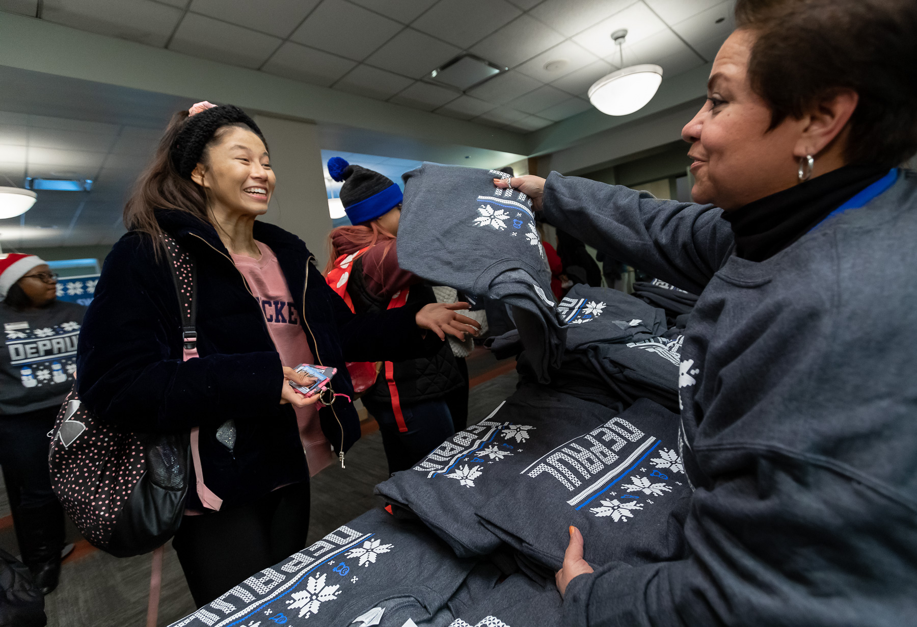 A student happily receives one of the coveted “ugly sweaters” from staff member Maria Toscano during the Ugly Sweater Party. (DePaul University/Jeff Carrion)